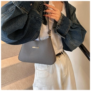 Detail of dark gray textured underarm bag with gold metal buckle and woven strap