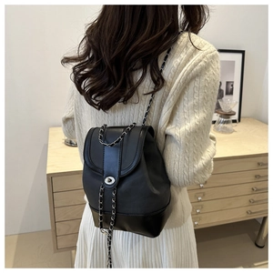 Chic black chain backpack shown on a model in a minimalist indoor lifestyle setting
