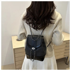 Detail of a black leather backpack with chain strap and silver metal twist lock