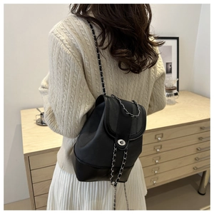 Detail of black leather chain bag with silver twist lock on beige knit sweater