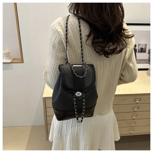 Detail of black mini chain backpack with silver twist lock on beige knit sweater