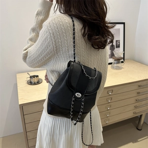 Fashionable black PU leather chain backpack for women shown on model in a cozy interior