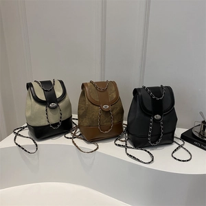 Three stylish chain backpacks in cream, brown, and black displayed on geometric stands