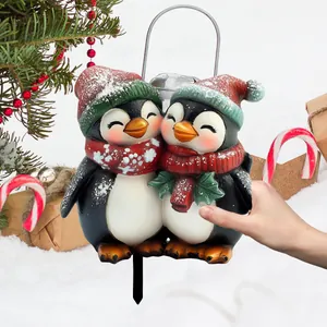Charming Christmas penguin garden stakes with festive hats in a snowy yard setting