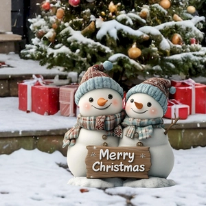 Dettaglio di figurine di pupazzi di neve con insegna Merry Christmas in un giardino innevato
