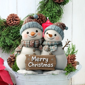 Dettaglio di due pupazzi di neve in resina che tengono un cartello Merry Christmas
