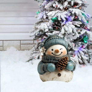 Dettaglio di un pupazzo di neve decorativo con cappello blu e pigna in un giardino innevato