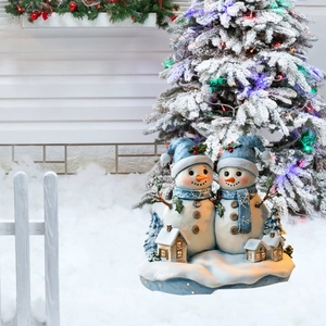 Detail of Christmas snowman garden stakes with glowing mini houses in snow yard