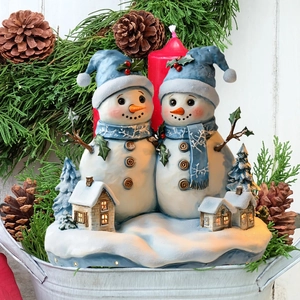 Detail of lit Christmas snowman resin ornament with micro village and knit style blue hats