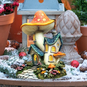 Detail of mushroom fairy house garden ornament with orange roof and glowing windows