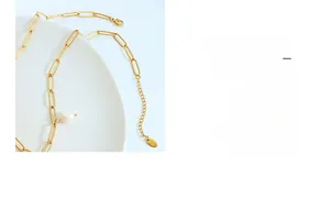 Detail einer goldenen Büroklammer-Kette mit weißem Tropfenperlen-Anhänger und Karabinerverschluss