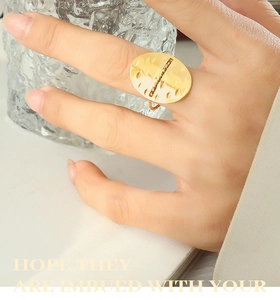 Detail of gold oval ring featuring hammered metal texture and vertical bead line