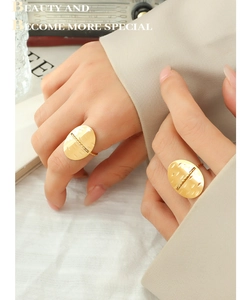 Detail of a matte gold oval ring with brushed texture and dotted line engraving