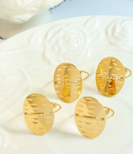 Detailed view of four gold oval rings with scratch textures on an embossed white ceramic tray