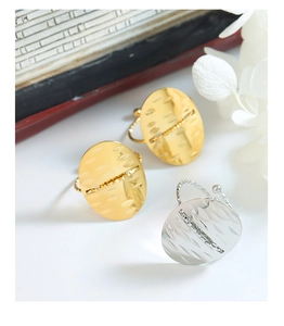 Macro shot of oval textured gold and silver adjustable rings on a minimalist white surface