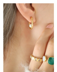 Gros plan d'élégantes boucles d'oreilles en U dorées avec perles et bagues assorties