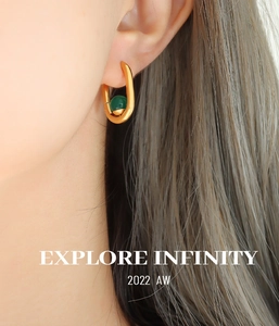 Gros plan d'une boucle d'oreille en U dorée avec agate verte portée par un mannequin