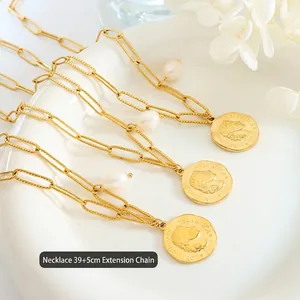 Goldene Büroklammerkette mit Barockperlen und Münzanhänger auf weißem Porzellanteller