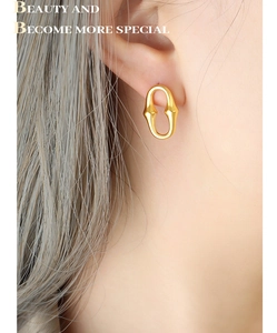 Gros plan de boucles d'oreilles ovales dorées en forme de U portées par un mannequin