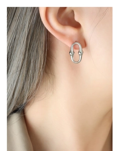 Gros plan d'une boucle d'oreille ovale géométrique minimaliste portée par un mannequin