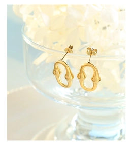 Gros plan de boucles d'oreilles dorées géométriques sur un verre avec des fleurs blanches