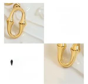 Détails macro de boucles d'oreilles ovales en U, plaquées or 18 carats sur acier titane