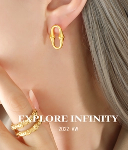 Détail de boucles d'oreilles dorées en U et bague texturée portées par un mannequin
