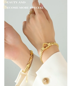 Detail of gold Cuban link heart bracelet and chain ring set on a model wrist