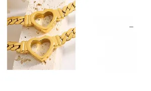 Detailed view of hollow heart charm on thick gold Cuban link chain over stone surface
