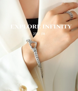Close-up of silver hollow heart chain bracelet and matching ring on model's wrist