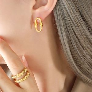 Boucles d'oreilles ovales dorées en U et bagues texturées pour femmes sur modèle