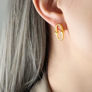 Boucles d'oreilles dorées géométriques ovales portées par un mannequin au style chic