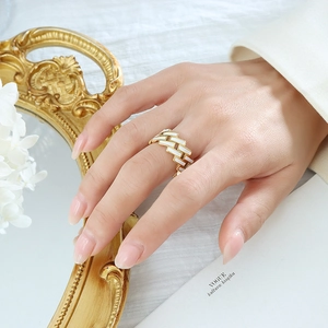 Bague croisée en or 18 carats avec émail blanc portée par un mannequin dans un décor chic