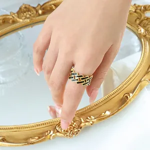Bague large dorée avec émail noir et motif géométrique rectangulaire sur la main