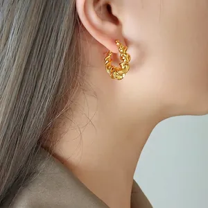 Golden twisted hoop earrings in French croissant style worn by a model for a stylish look