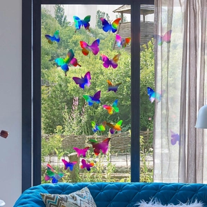 Vibrant laser butterfly wall decals displayed on a bright window with a garden view