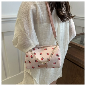 Details einer rosa Cord-Kissentasche mit Erdbeerdruck und dekorativer Metallkette