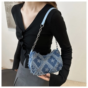 Detail of denim underarm bag featuring star patchwork with frayed edges and chain strap