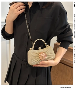 Détail de la pochette de soirée dorée avec fleur en strass et bandoulière chaîne