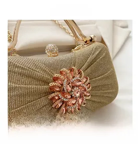 Gros plan détaillé de la pochette dorée champagne avec fleur en cristal et fermoir diamant
