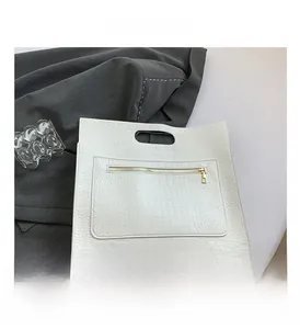 Λεπτομέρεια λευκής τσάντας tote με ανάγλυφο κροκόδειλο και χρυσό φερμουάρ μπροστά