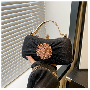 Détail d'une pochette de soirée plissée noire avec grande fleur de tournesol en strass