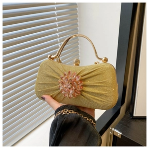 Détail de la pochette plissée or champagne avec fleur en cristal et boucle diamant