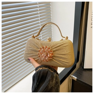Détail d'une pochette de soirée dorée à paillettes avec fermoir fleur en strass et anse