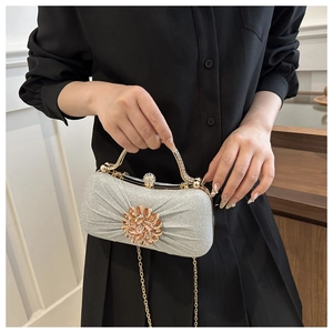 Gros plan d'une pochette argentée pailletée avec une boucle fleurie en strass colorés
