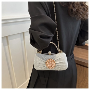 Détail de pochette de soirée argentée avec fleur en strass et poignée en métal chic
