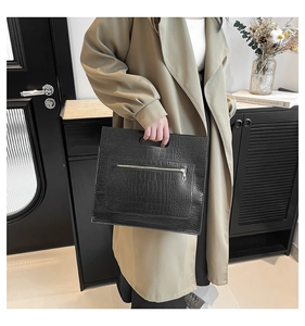 Détail du sac cabas noir motif crocodile avec poignée découpée et fermeture éclair argentée