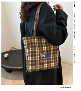 Detail of checkered tote bag featuring a cartoon dachshund print and leather shoulder strap