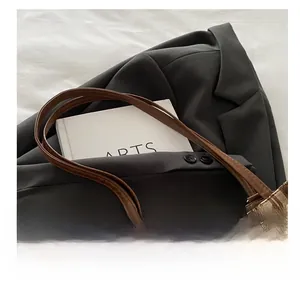 Close-up of vintage brown plaid tote bag with durable leather handles on gray blazer