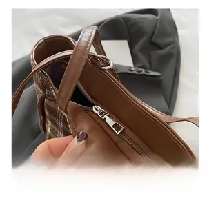 Close-up of the smooth silver metal zipper and brown leather trim on the plaid tote bag